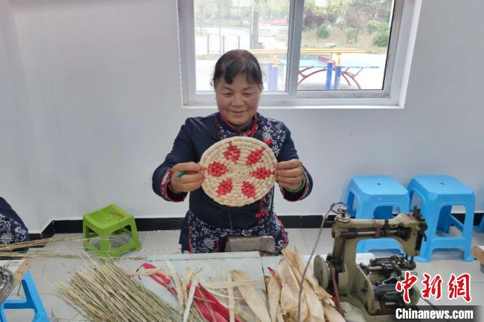 图为孙娥花展示草编工艺品。　梅镱泷 摄
