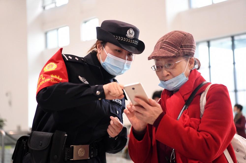 2月25日，女子巡逻队队员秦雯（左）在合川站候车大厅为旅客提供帮助。