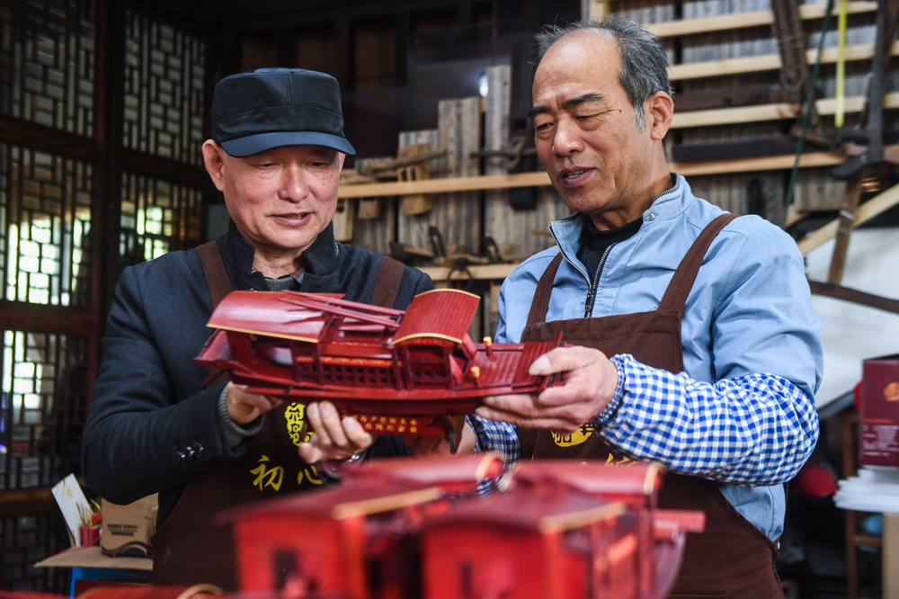 4月13日，67岁的韩鸣华（左）在检查即将出厂的红船模型。