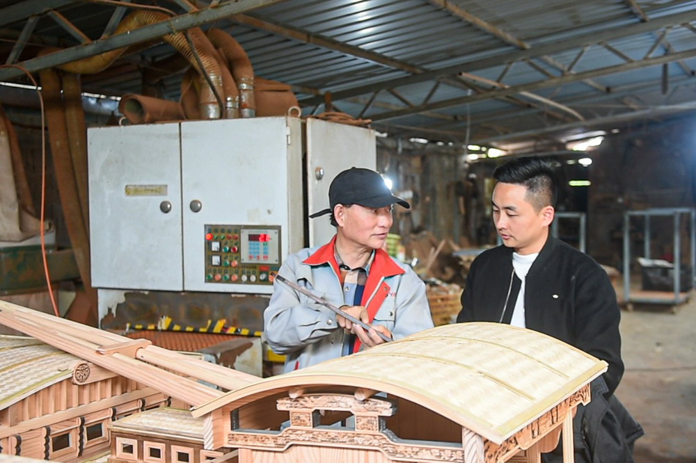 4月13日，韩鸣华（左）在车间内与自己的徒弟交流红船模型部件的制作技艺。
