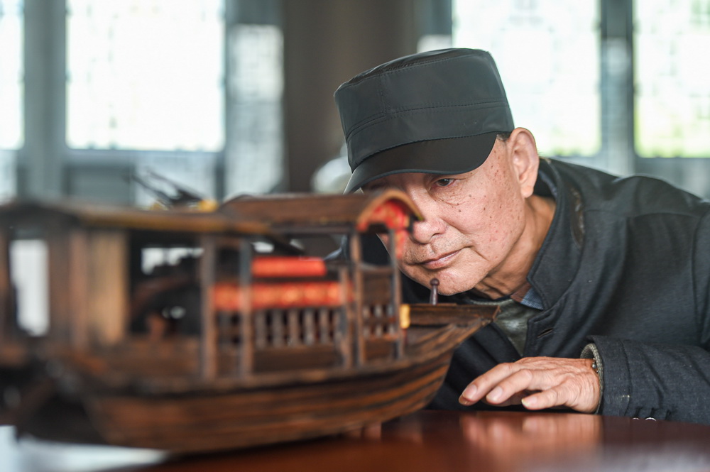 4月13日，韩鸣华在仔细端详一艘制作完成的红船模型。
