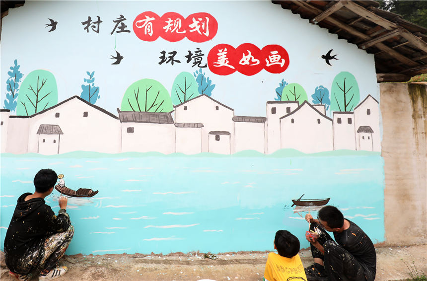 5月7日，在湖南省资兴市唐洞街道高牌村，大学生志愿者在创作墙体绘画。李科摄
