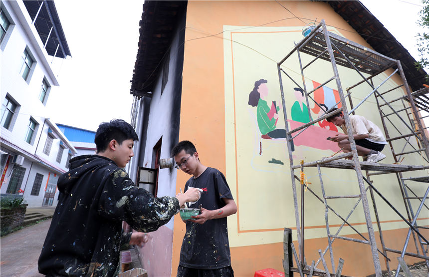 5月7日，在湖南省资兴市唐洞街道高牌村，大学生志愿者在创作墙体绘画。李科摄
