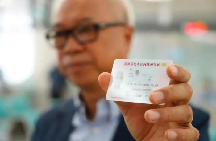 图为2020年10月15日，香港居民刘先生在上海出入境管理局办证接待大厅领到编号001的回乡证，成为首位在内地直接换补发回乡证的港澳居民。图片来源：国家移民管理局 蒋琦超 摄