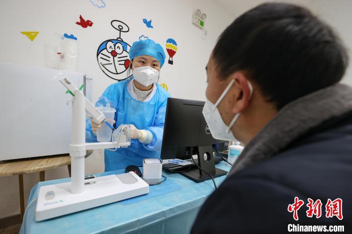 12月13日，贵阳南明区小车河街道一卫生服务中心内，医护人员在给市民讲解疫苗接种方式。　瞿宏伦 摄