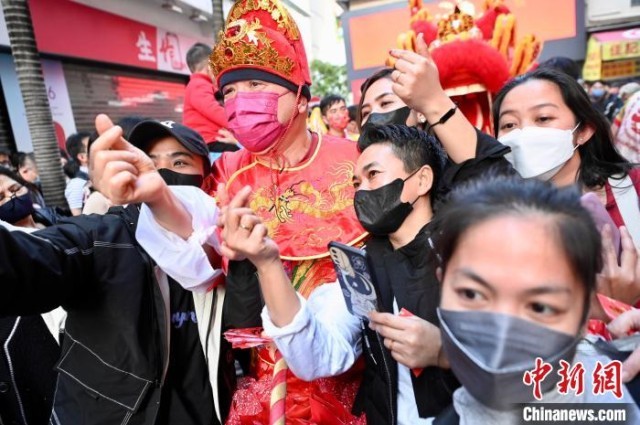 市民及游客等与财神扮演者合影。　李志华 摄