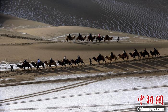 1月27日，游客骑骆驼畅游敦煌鸣沙山。　张晓亮 摄