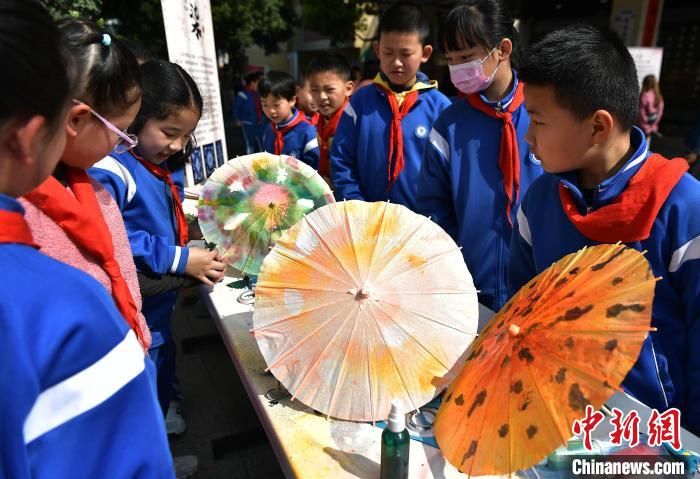 图为小学生在活动上参观了解扎染技艺在福州油纸伞制作上的运用。　张斌 摄