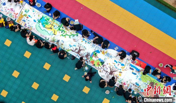 3月21日，在山东省临沂市兰山区柳青街道中心幼儿园，孩子们正在绘制节水主题的画卷。(无人机照片) 许传宝 摄