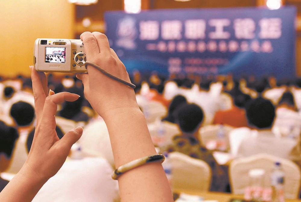 一位与会的台湾代表高举手中的相机记录下海峡职工论坛大会的场景。（资料图片）