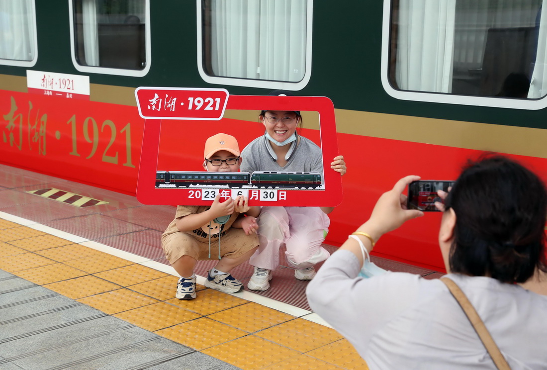 6月30日，旅客在Y701次“南湖·1921”红色旅游列车旁拍照打卡。新华社记者 刘颖 摄