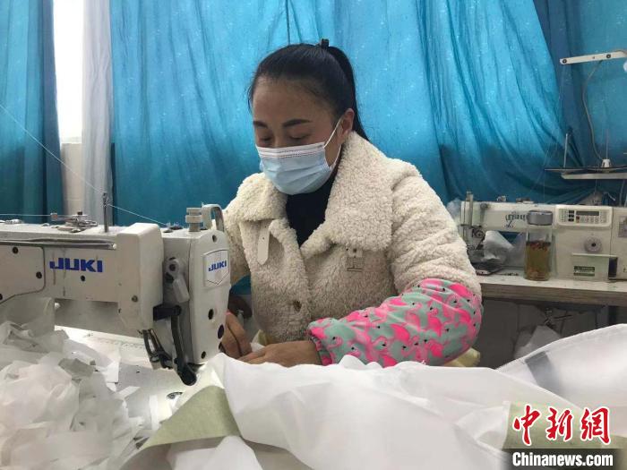37岁的胡青丽正在缝纫机上忙着手上的工作。　刘鸿鹤 摄