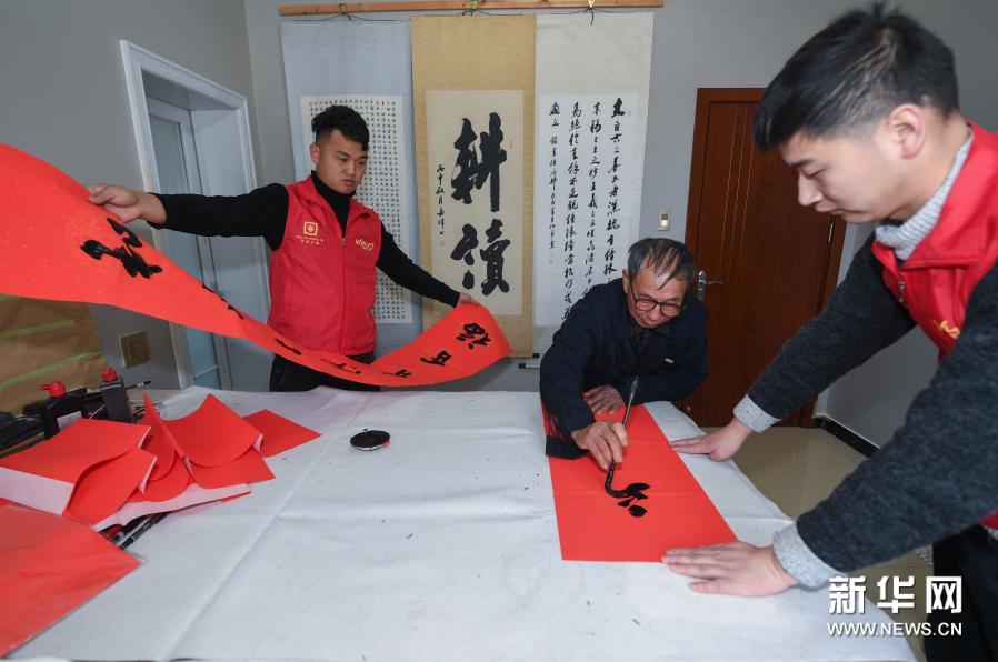 1月21日,中泰街道岑岭村的党员志愿者和当地乡贤沈炳华(中)在书写赠送