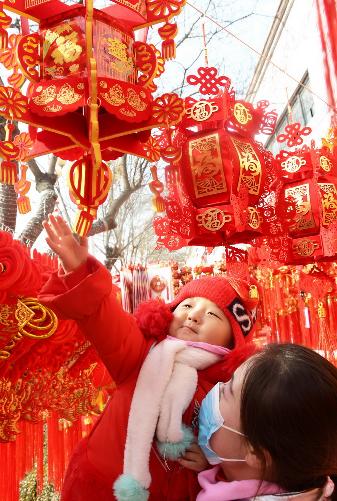 1月31日，家长带着孩子在永靖县刘家峡镇一市场挑选节庆饰品。