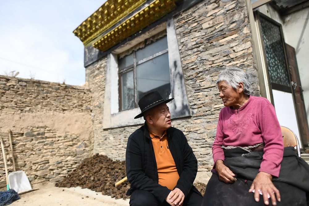 3月9日，在称多县拉布乡郭吾村，尼玛（左）与才尕老人交谈，尼玛计划帮助才尕老人修复她家的传统建筑。