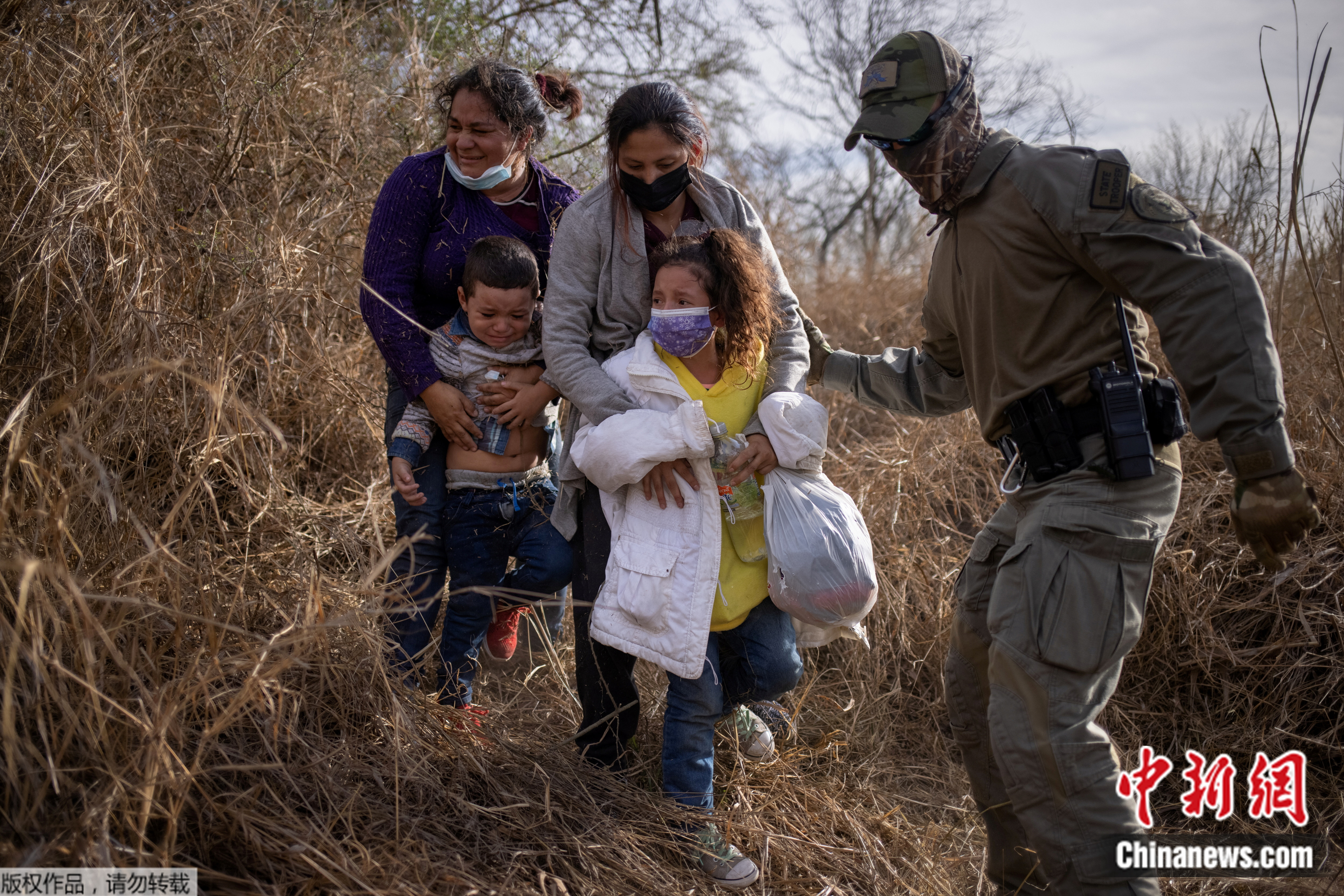 图4：在美国得州里奥格兰德，边境执法者要求躲在灌木丛中的非法移民家庭走出来，以便将他们戴上手铐逮捕并转移。