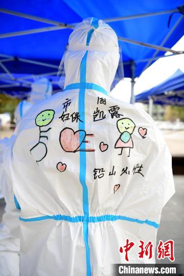 在江西省上饶市铅山县河口镇文化广场，做完核酸检测的医护人员正在防护服上画上各种各样的美图。　丁铭华 摄