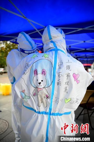 在江西省上饶市铅山县河口镇文化广场，做完核酸检测的医护人员正在防护服上画上各种各样的美图。　丁铭华 摄