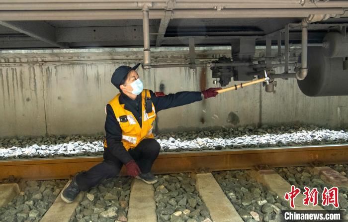 女检车员李军正在检查列车制动管系。　刘忠俊 摄