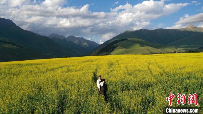 油菜花盛开期，游客在新疆和静县巩乃斯镇万亩油菜花前游玩。　确·胡热？　摄