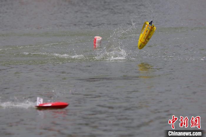 比赛很是激烈，正在进行绕标追逐赛的两艘航模相撞，其中一艘(黄色)从水中飞起后又落下。　泱波 摄