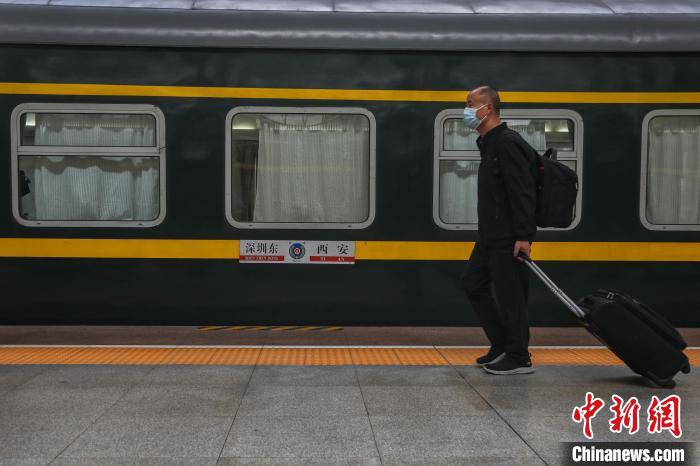 图为一位旅客携带行李从一列火车旁走过。　刘力鑫 摄