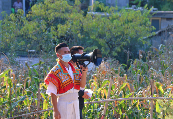 2022年9月19日，纳雍县昆寨乡大寨村，村主任刘坚和同事进村入户用苗族和汉语宣传疫情防控知识 。