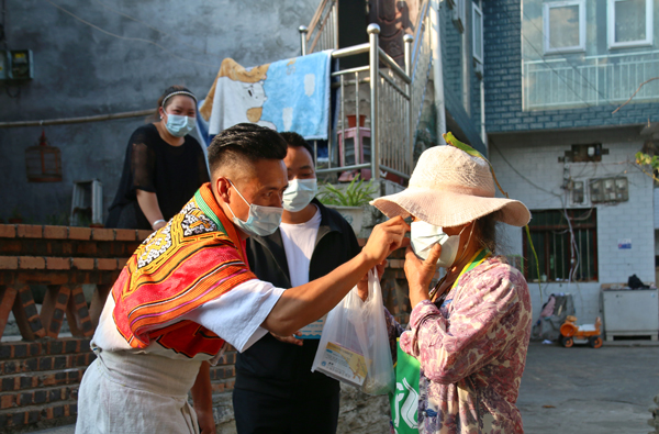2022年9月19日，纳雍县昆寨乡大寨村，村主任刘坚和同事进村入户宣传疫情防控知识并指导村民正确戴口罩 。