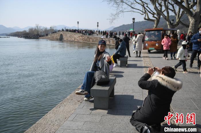 游客在杭州西湖边以断桥为背景拍照。　王刚 摄