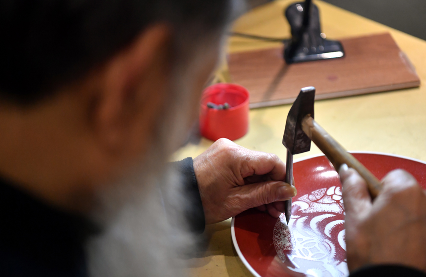 在“非遗匠心馆”的工作室内，李强正在用锤子和凿钉刻瓷。 人民网 时雨摄