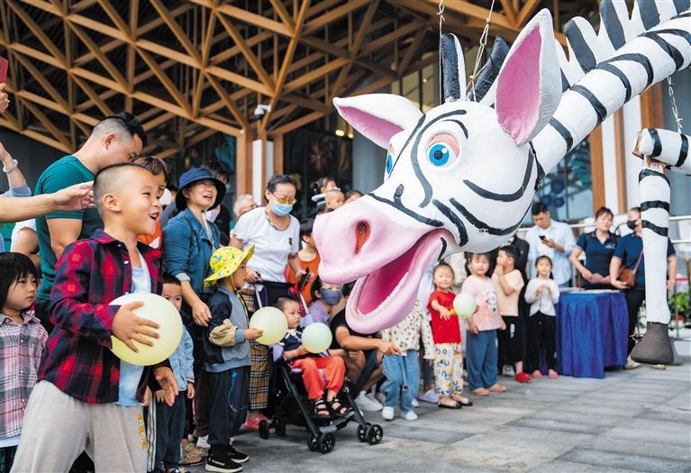 4月8日，小朋友在万宁王府井与大木偶互动。