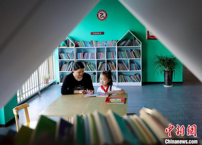 在肥西县上派镇金星和园城市阅读空间，一名家长陪伴孩子阅读。　陈家乐 摄