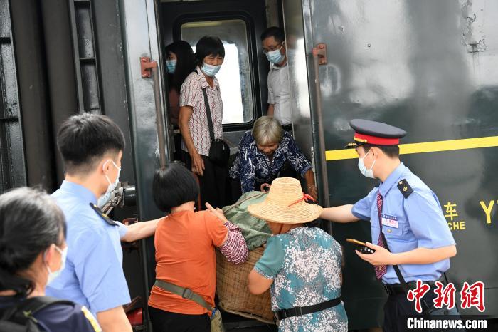 吴金连在年轻同行及列车员的帮助下，将水果搬下车。　蒋雪林 摄