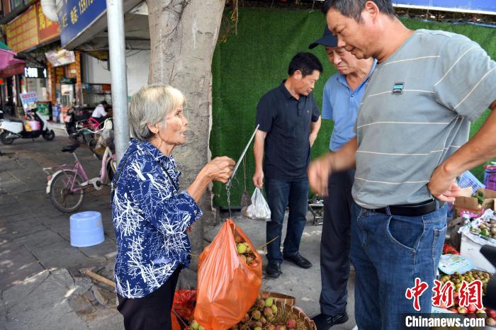 身体单薄的吴金连在火车站前不远处的丁字路口摆卖水果。　蒋雪林 摄