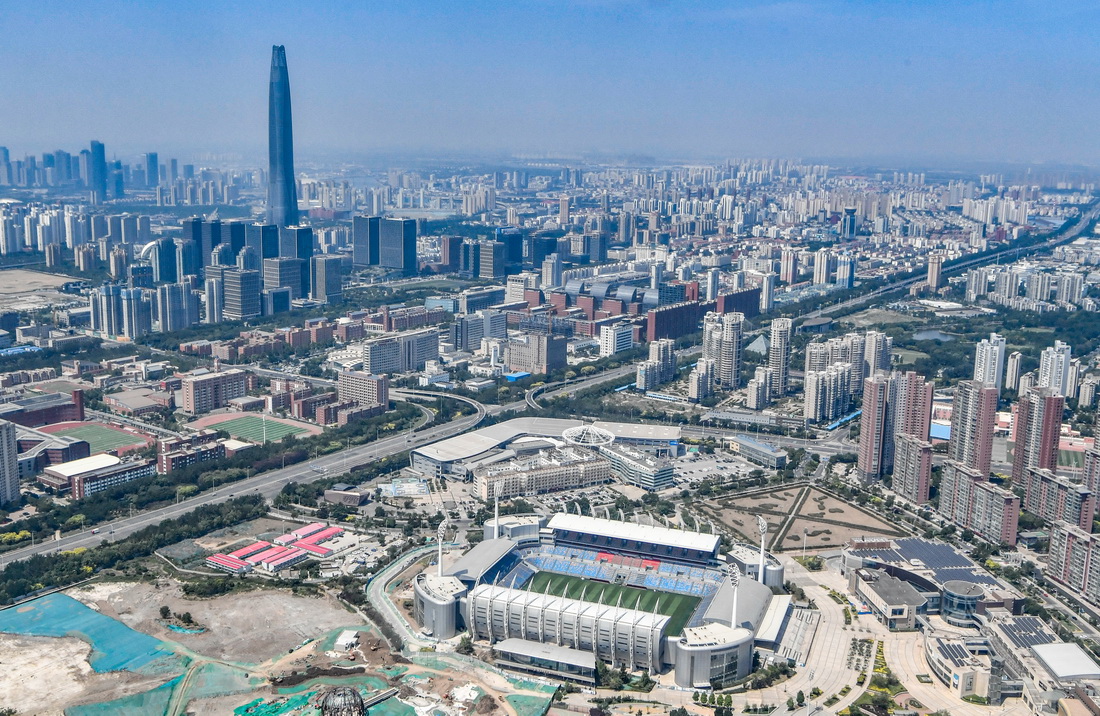 这是6月16日从直升机上拍摄的位于天津滨海新区的天津泰达足球场和远处的天津周大福金融中心。