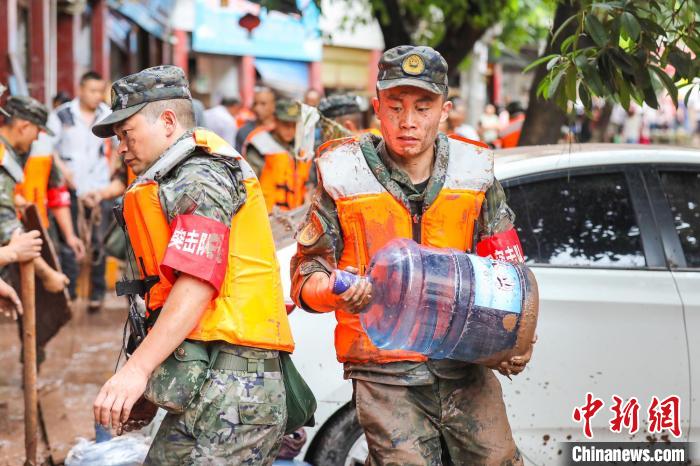 图为武警官兵帮助受灾群众转移物资。　李东 摄